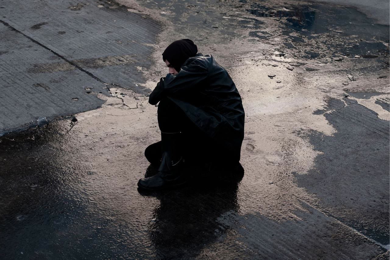 Camille Keller seated on wet pavement